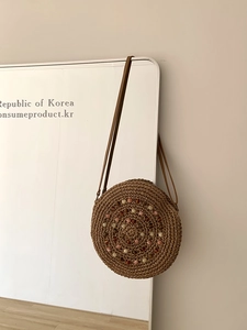 Macro detail of handwoven round straw bag with colorful spiral beads and leather strap