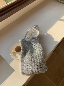 Detail of silver metallic crochet tote bag with intricate textured scallop pattern