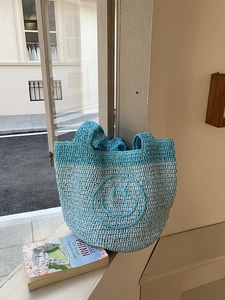 Detailed close-up of handmade crochet tote bag featuring blue patchwork and smile pattern