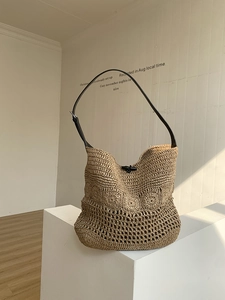 Detail of woven straw shoulder bag featuring floral crochet pattern and leather strap