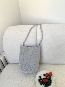 Vue de dessus d'un sac seau tissé argenté sur un canapé blanc avec des fruits