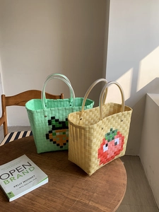 Detail of hand-woven plastic tote bag with pixelated fruit patterns and clear tube handles
