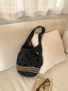 Détail du motif floral au crochet et base rayée sur un sac cabas tissé noir élégant