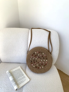 Detail of round straw bag with colorful spiral beadwork and a leather shoulder strap