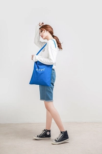 Blaue Canvas-Tragetasche mit Accept-Schriftzug am Model zur Darstellung der Passform