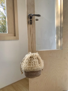 Detail einer handgewebten Stroh-Eimertasche mit zarten beigen Tüll-Spitzenschichten