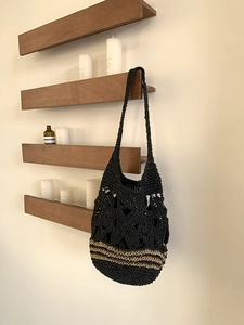 Gros plan d'un sac cabas au crochet noir à rayures beige suspendu au mur en bois