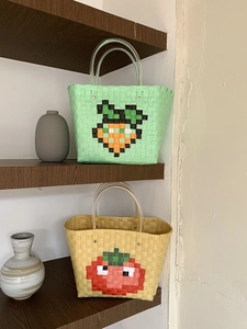 Detail of hand-woven basket bags with pixel fruit patterns and clear plastic handles