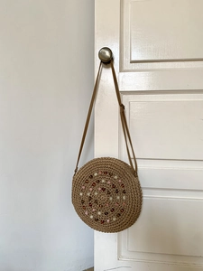 Detail of round straw bag with colorful spiral beadwork and thin leather strap