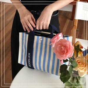 Détail du cabas en toile à rayures bleues avec poignée Goodluck sur table blanche