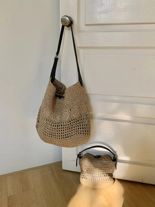 Detailed view of woven straw beach bags with black leather straps and horn buckles