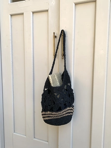 Détail du sac cabas en crochet noir avec motifs floraux ajourés et rayures beige