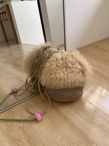 Detailaufnahme der beigen Stroh-Beuteltasche mit Tüllbesatz und Kordelzugträgern