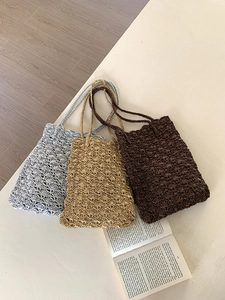 Detail of hollow woven handbags in gold, silver and brown with a wave pattern