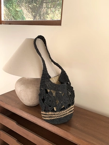 Détail du motif floral au crochet et du fond rayé sur un sac fourre-tout noir