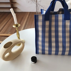 Detail of blue and white checkered canvas tote bag on a white table in home setting