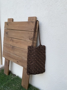 Close-up of hand-woven crochet tote bag with textured fan patterns on a wooden display