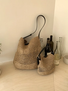 Detail of hand-woven straw bags with floral crochet patterns and black leather straps