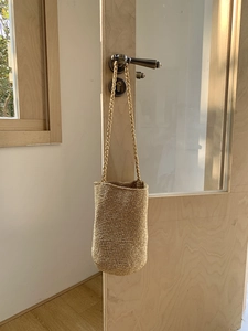 Détail du sac seau tissé à la main avec texture paille fine et bandoulière ronde