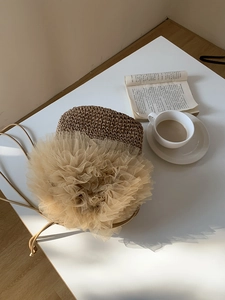 Detail der handgefertigten Stroh-Beuteltasche mit beiger Mesh-Spitze und schmalem Gurt