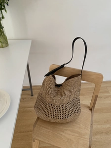 Detail of hollow crochet beach bag with floral pattern and adjustable black strap