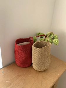 Détail du sac seau tissé rouge et or avec une texture en fibres métalliques brillantes