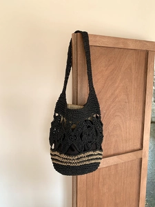 Détail d'un sac cabas en crochet noir avec fleurs ajourées et rayures kaki sur le dessous