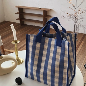 Close-up of blue and white checkered canvas tote bag with reinforced woven straps