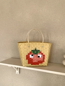 Detail of pixel tomato pattern on woven beige beach tote with clear round handles