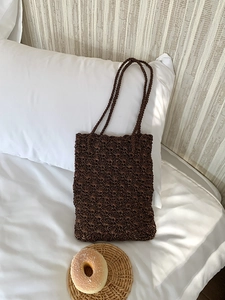 Detail of brown crochet tote bag with shell stitch pattern on a soft pillow