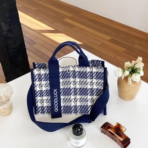 Détail du cabas en tweed bleu et blanc avec sangle GOODLUCK sur table blanche