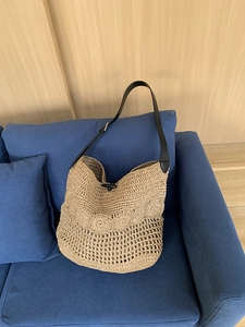 Detail of straw shoulder bag with horn buckle closure and hollow woven patterns