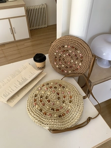 Detail of round straw bags featuring spiral beadwork and adjustable leather straps