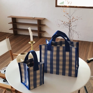 Detail of blue checkerboard canvas tote bags in large and small sizes on a white table