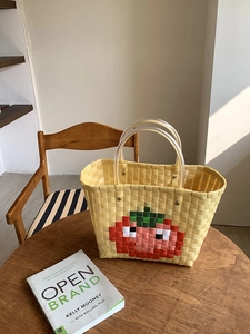 Detail of yellow woven beach bag with red pixel tomato pattern and transparent PVC handles