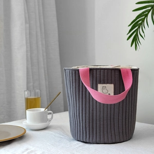 Détail du sac cylindrique matelassé gris foncé avec poignée tissée rose contrastée