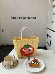 Detail of hand-woven tote bag with red tomato pattern and clear circular handles