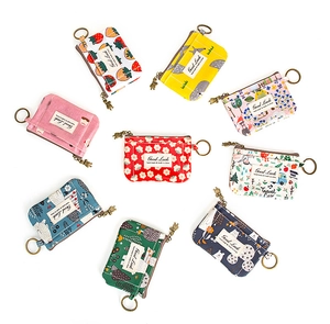 Divers porte-monnaie en toile aux motifs colorés avec porte-clés en métal sur fond blanc