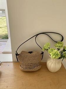 Detail of woven straw beach bag with bamboo toggle closure and slim leather strap