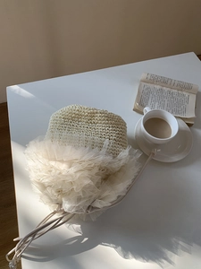 Detailansicht eines Strohhuts mit Tüllspitze auf einem gemütlichen Couchtisch