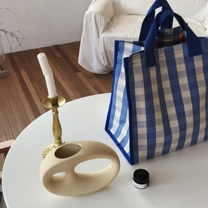 Detail of blue and white checkered canvas tote bag with reinforced blue strap handles