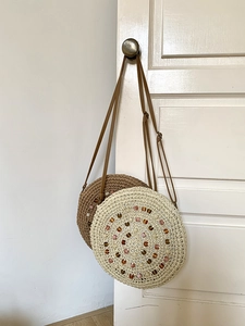 Detail of round handmade straw bags with colorful bead embellishments and slim straps