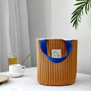 Détail du sac matelassé moutarde avec poignées bleues et patch alpaga minimaliste