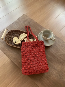 Detail of red handmade crochet tote bag with wave petal texture on wooden table