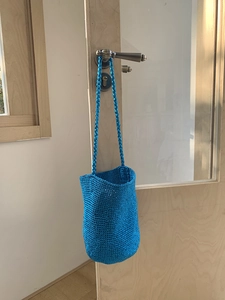Sac seau tissé à la main bleu vif avec longue bandoulière suspendu à une poignée de porte