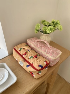 Gesteppte Taschen für Haartrockner in Orange und Floral-Rosa auf einem Holztisch