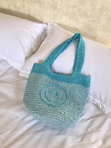 Handmade bohemian knit mini tote bag with smiling face pattern in blue contrast colors