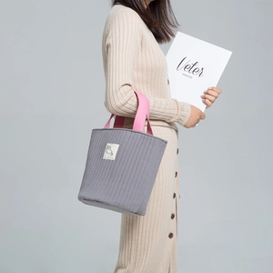 Détail du sac seau matelassé gris avec poignées roses et écusson d'animal mignon
