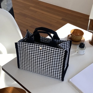 Détail du cabas en toile pied-de-poule avec sangle noire et fermeture à bouton argenté
