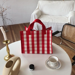 Close-up of a red and white checkered canvas tote bag in a cozy home setting